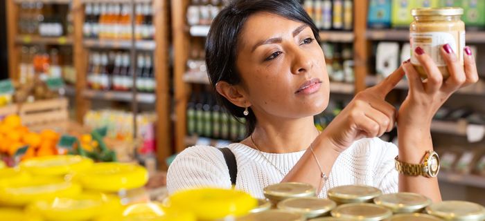 Woman reading a food product label in a shop, checking nutritional information
